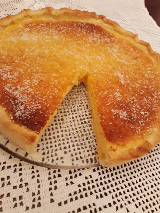 tarte de coco e natas dourada, cremosa e polvilhada com coco ralado.
