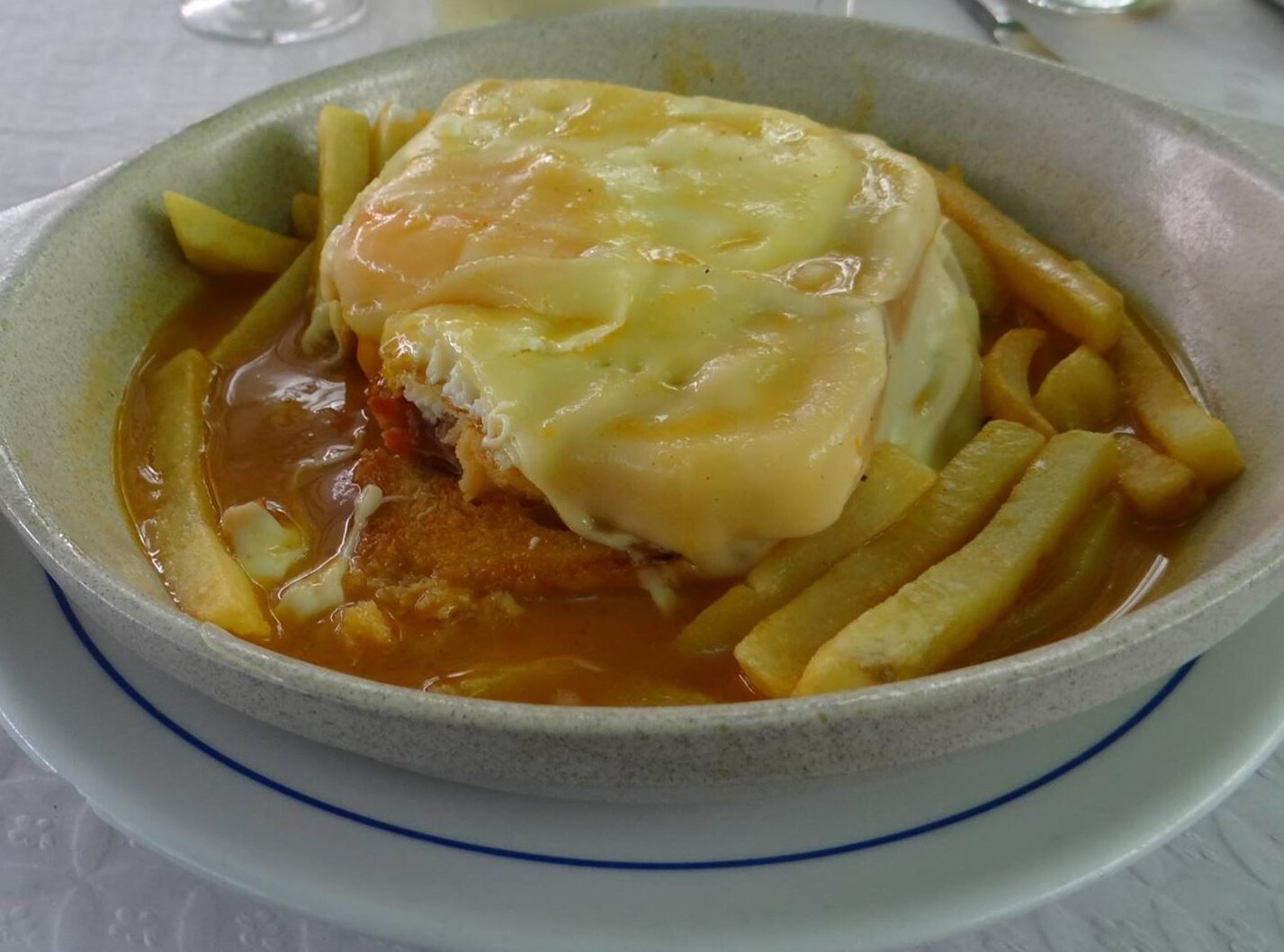Francesinha à moda do Porto com molho picante, queijo derretido e bife de vaca, prato tradicional português.