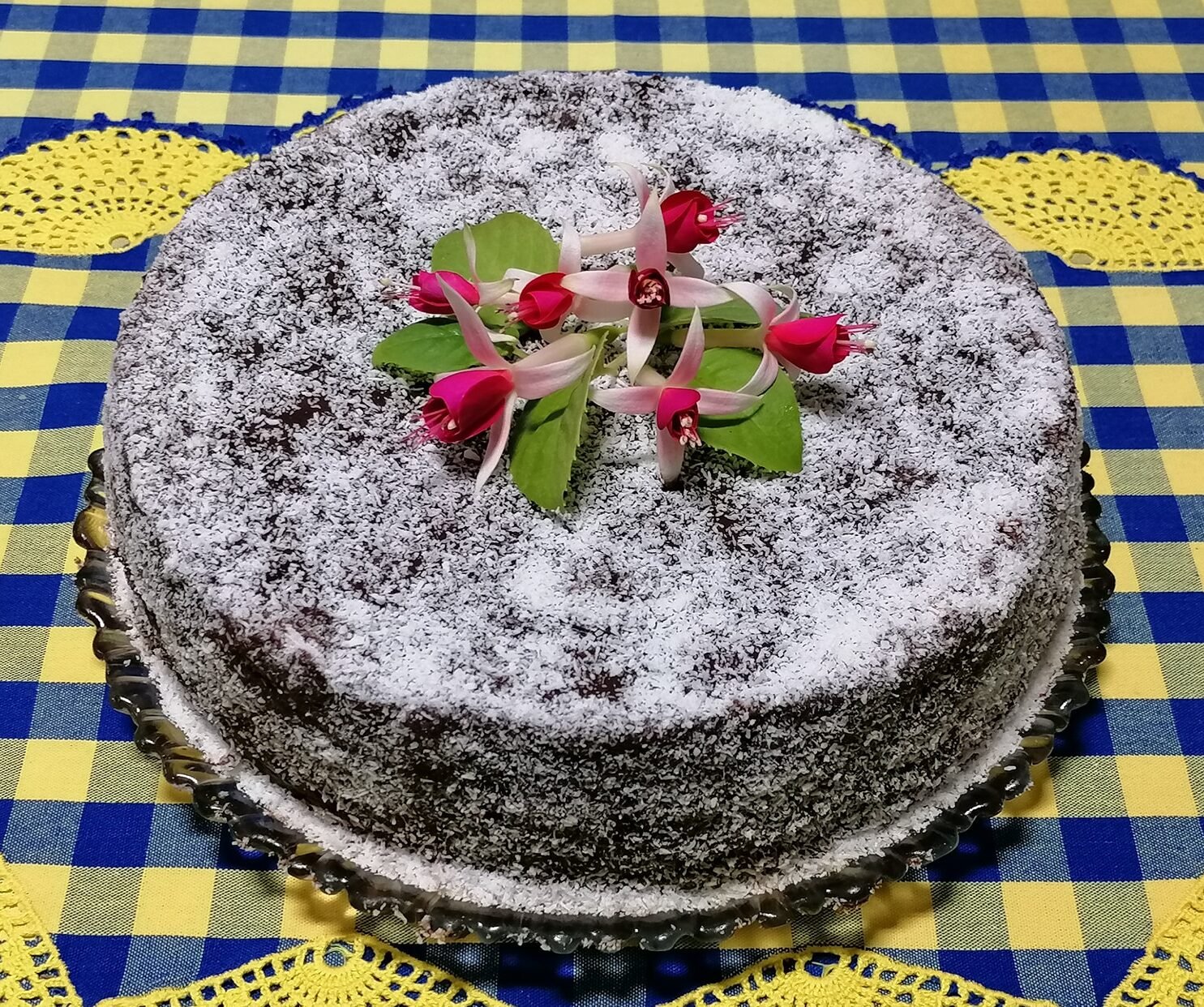bolo encharcado com coco e cobertura de chocolate, húmido e fofo, decorado com coco ralado.
