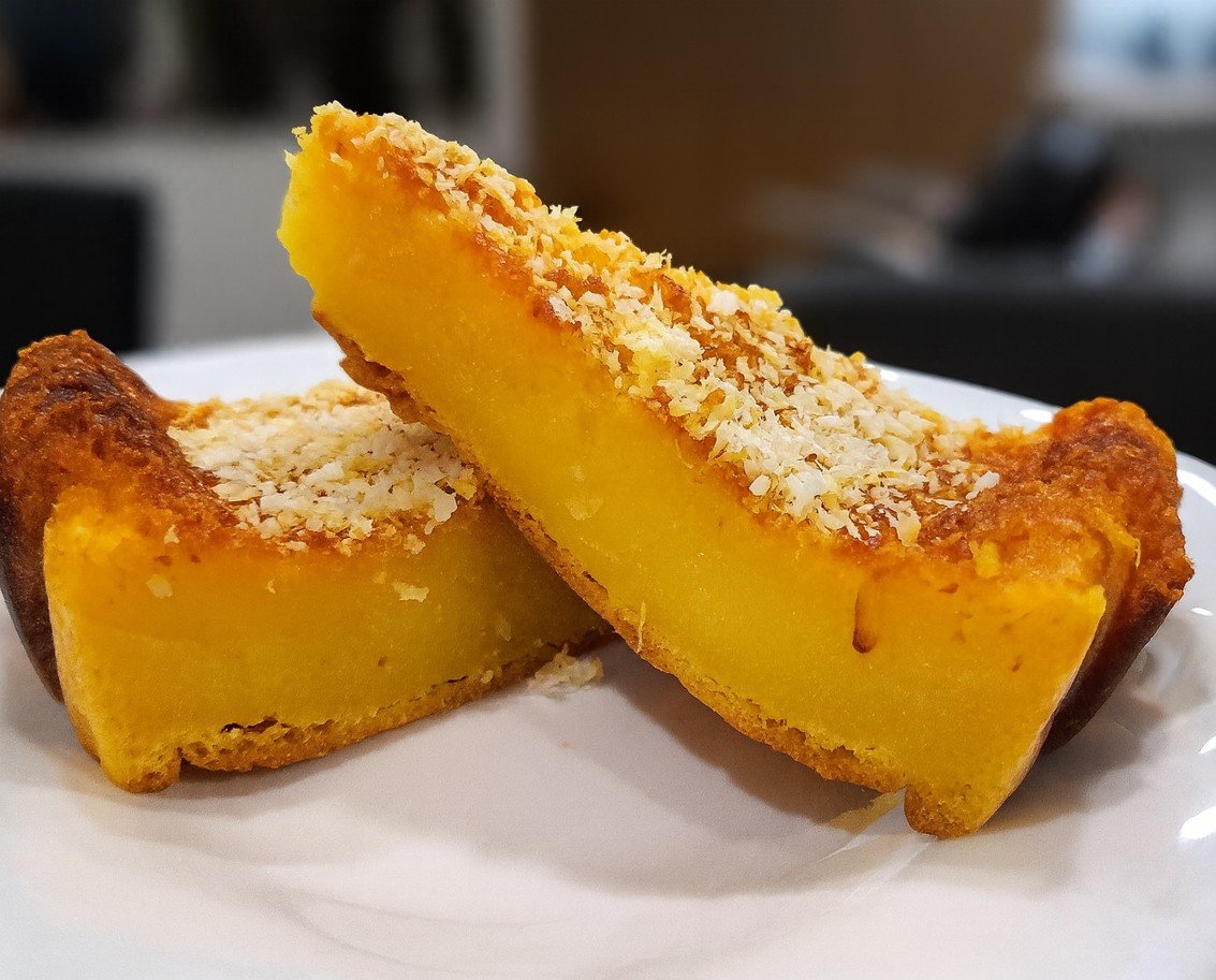 Fatias de queijada de laranja cremosa com cobertura de coco crocante servidas num prato branco.